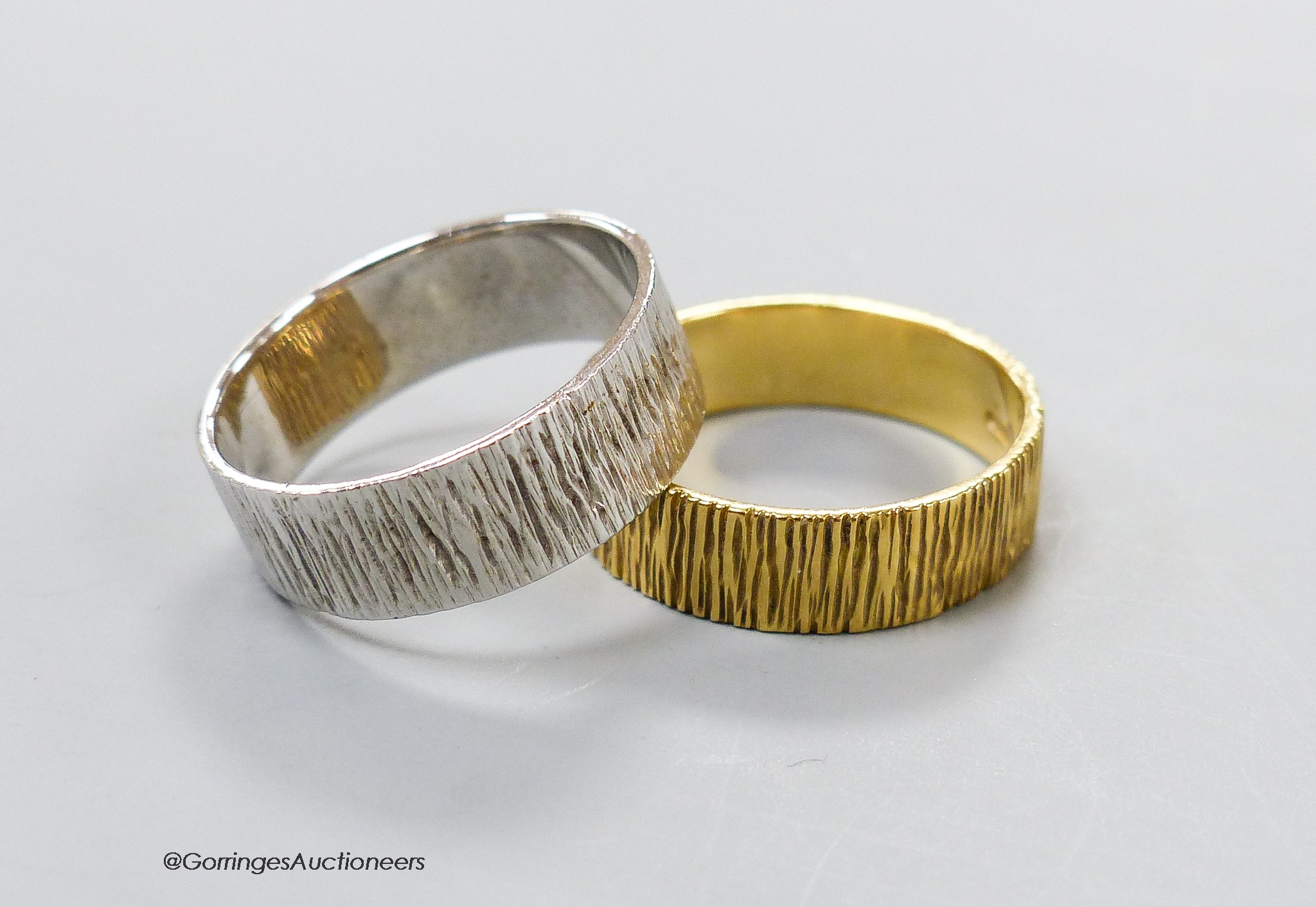 A modern textured 18ct gold band, size S, 5 grams and a similar 9ct white gold band, size S, 4.7 grams.